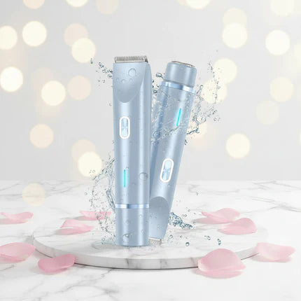 Two silver hair trimmers on a marble surface with pink petals and a blurred light background